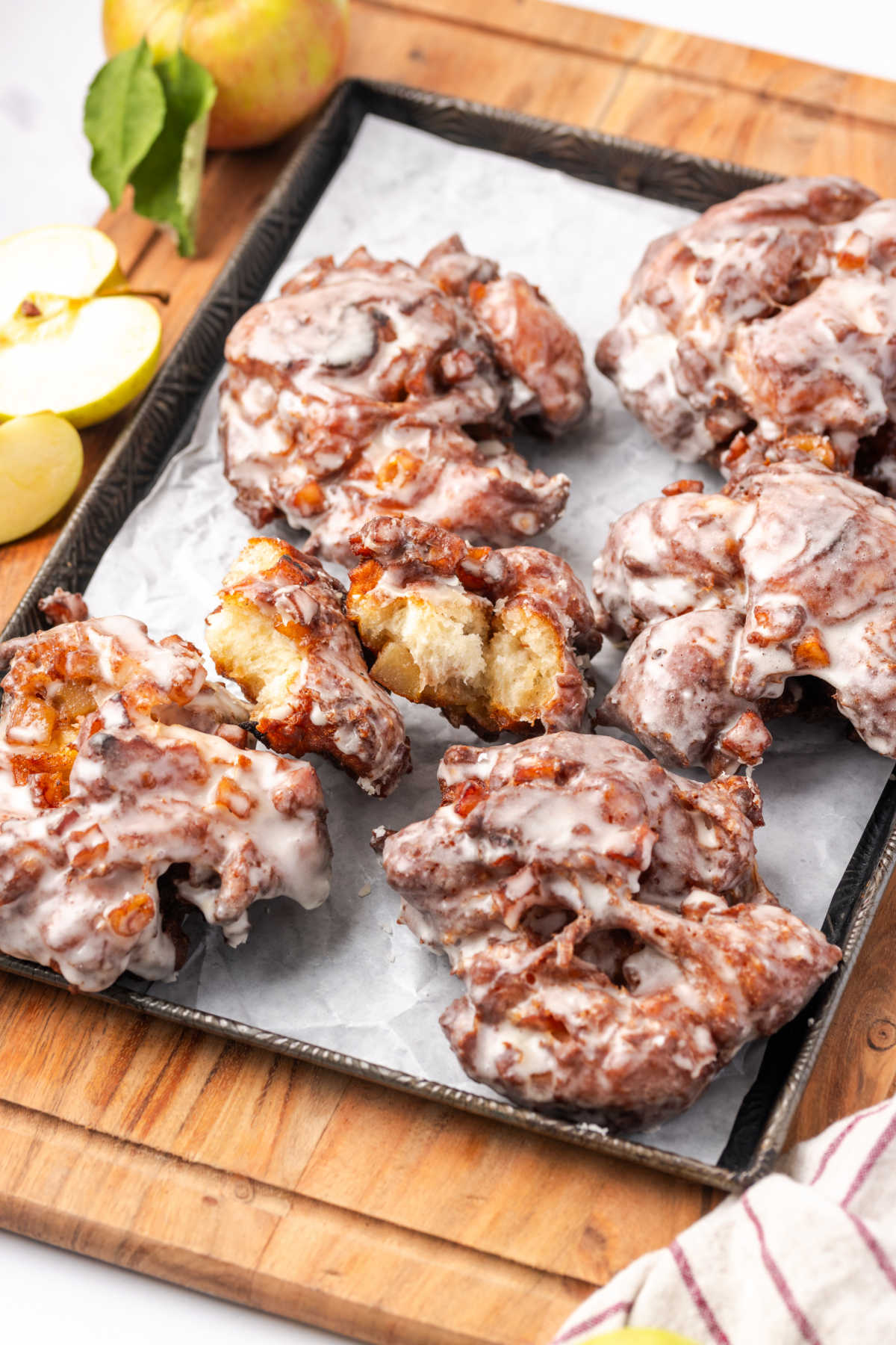Apple fritters with glaze on sheet pan.