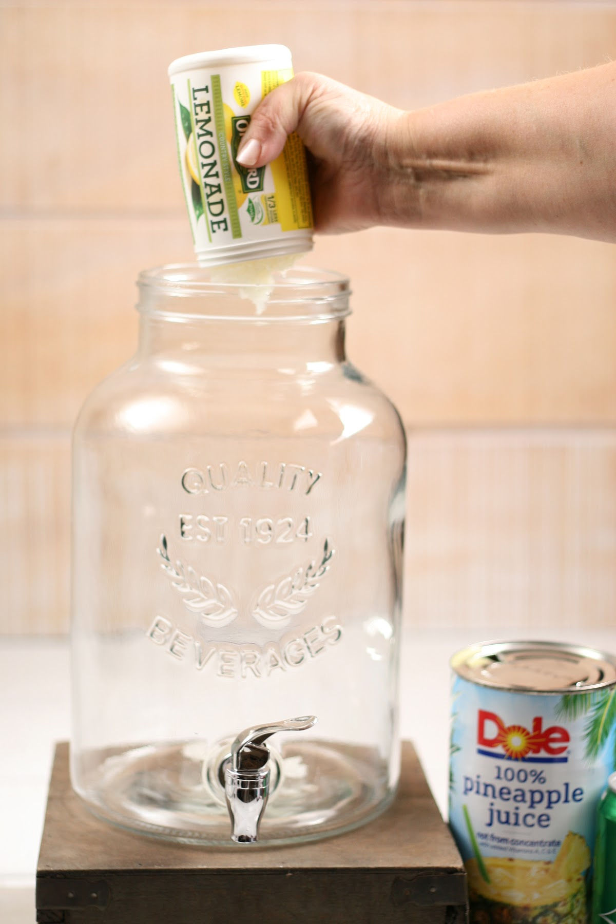 Squeezing frozen lemonade into clear glass drink dispenser.