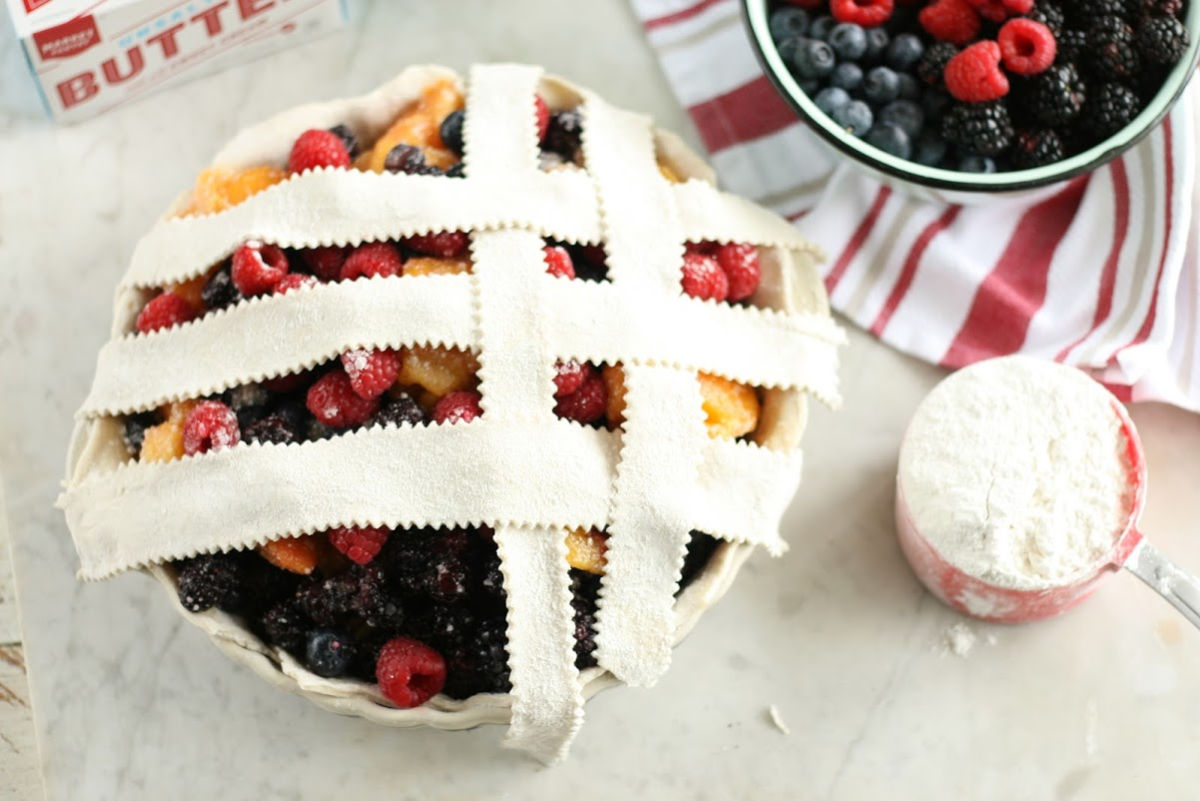 weaving a lattice crust on mixed berry pie.