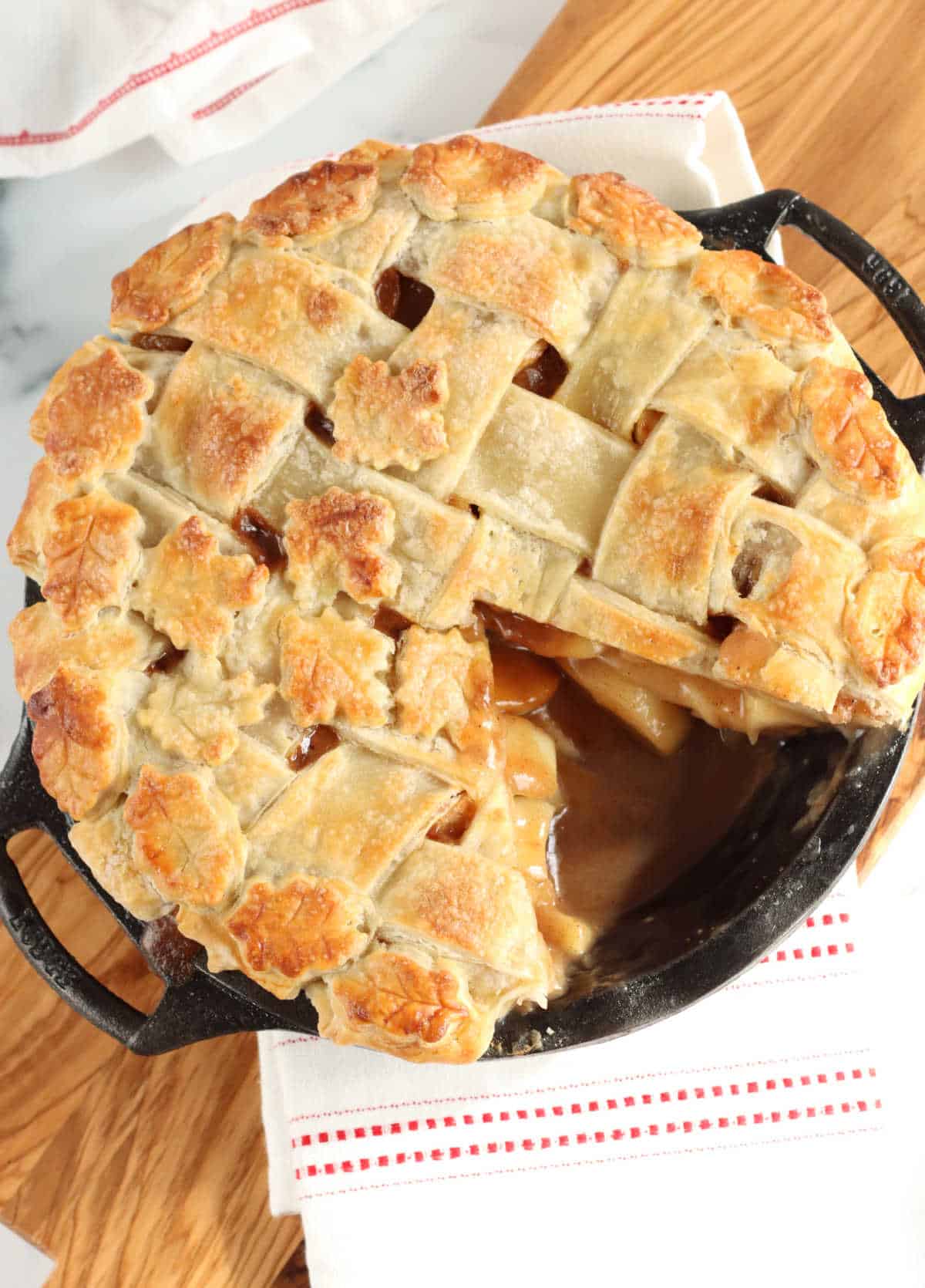 Apple pie in cast iron pie pan with lattice crust, slice cut out of it.