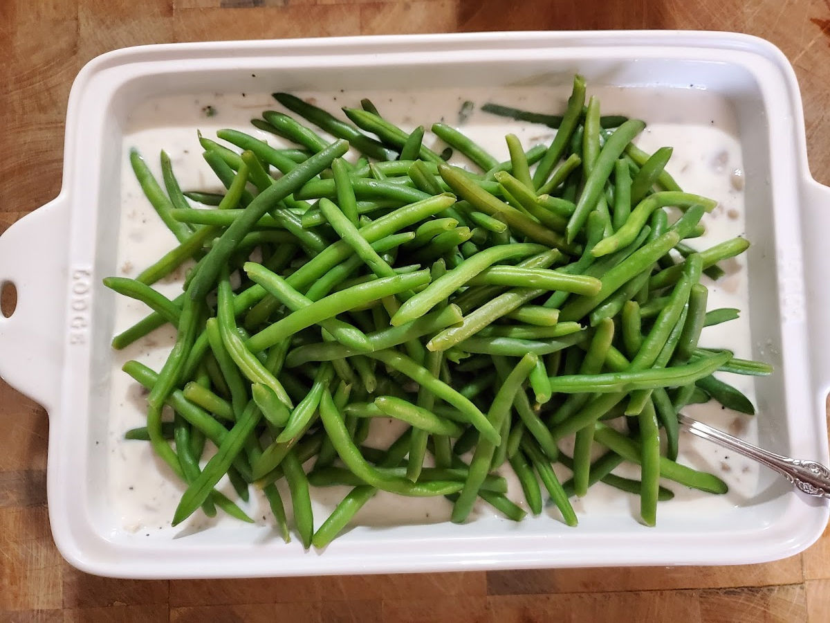 blanched green beans in white ceramic rectangle baking dish on butcher block.