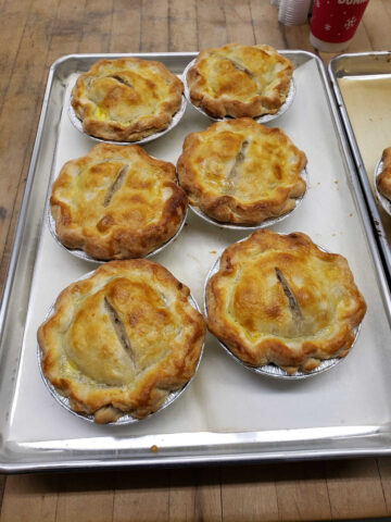 small meat pies on a sheet pan lined with white parchment paper.