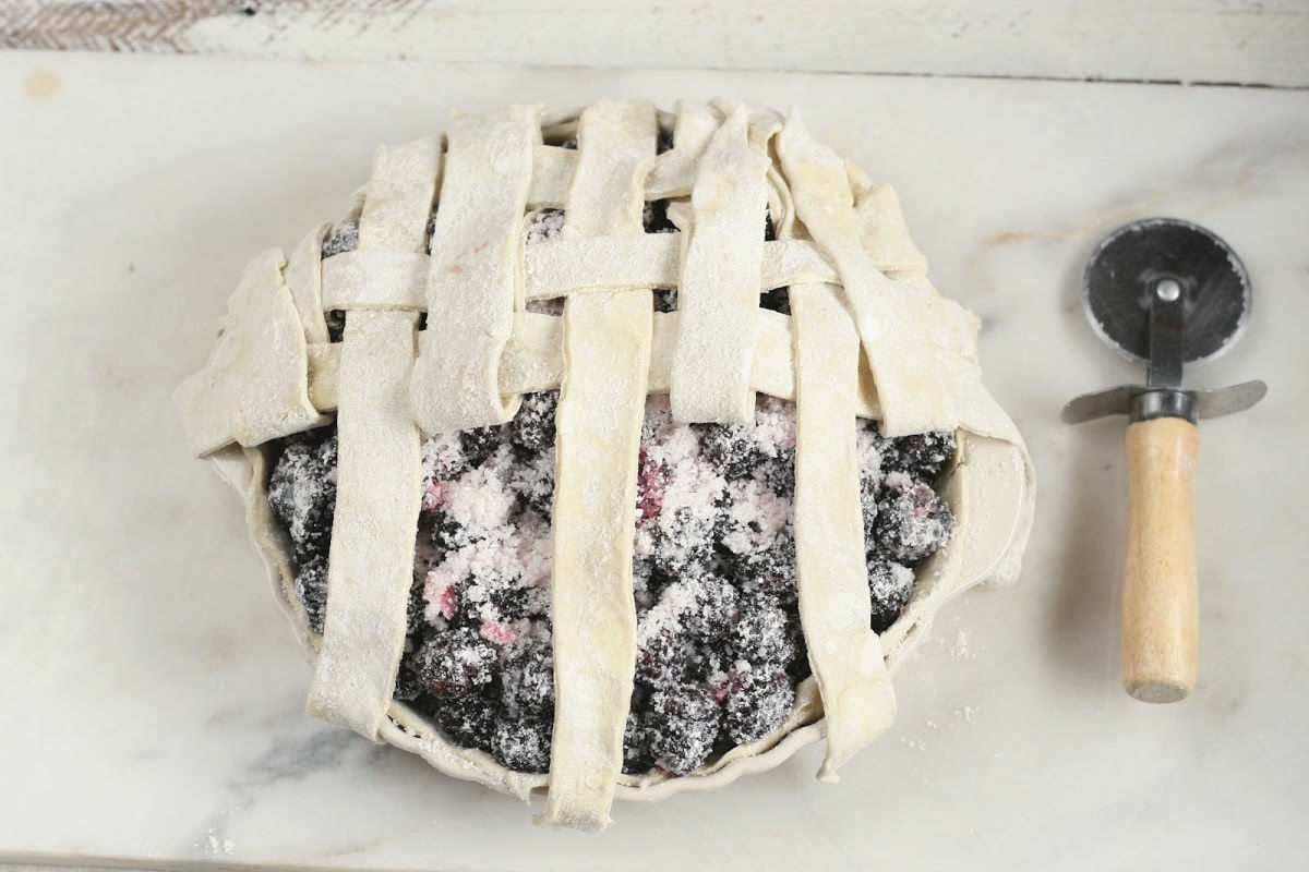 blackberry pie weaving lattice crust, small pastry cutter to right.