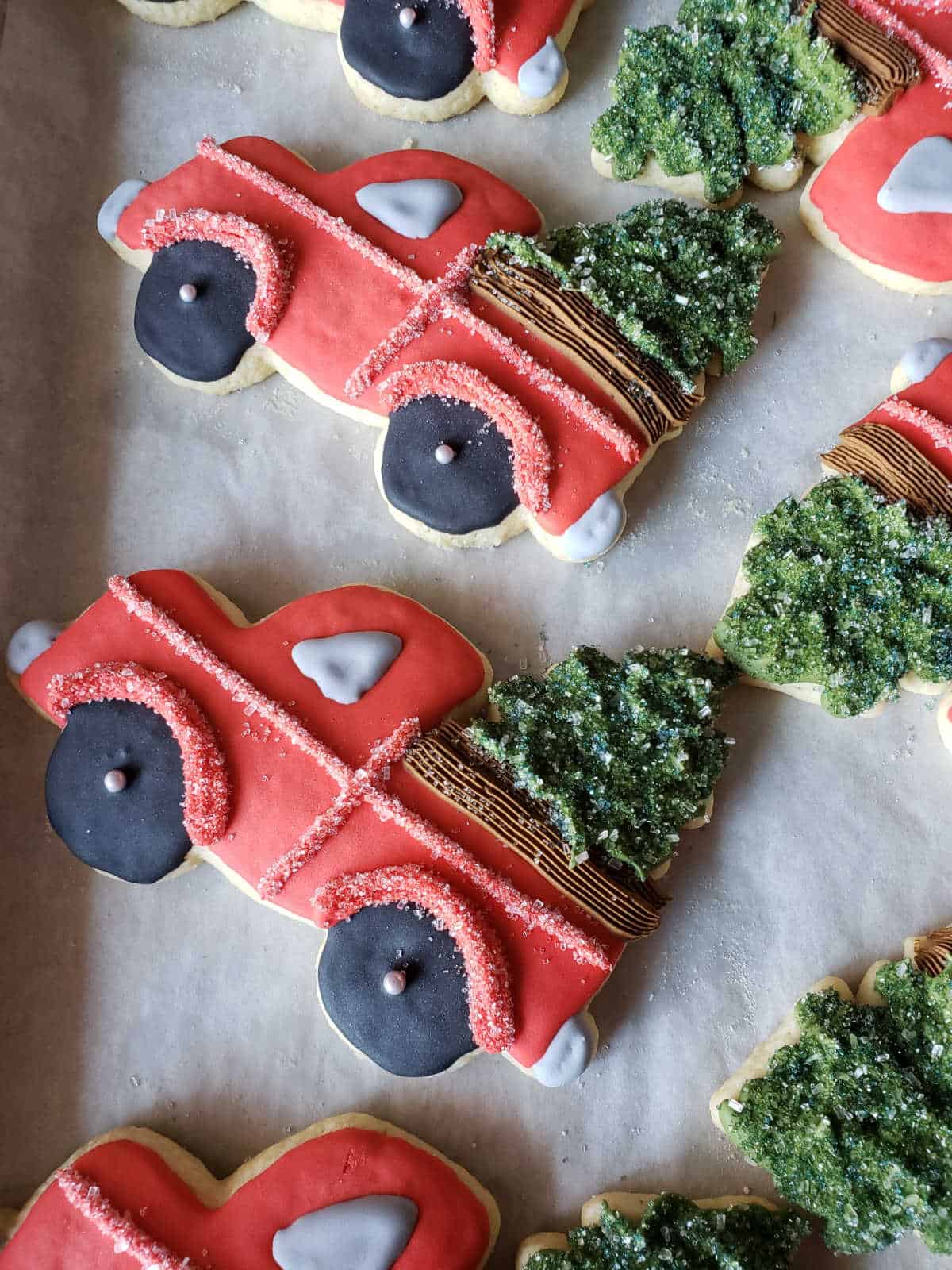 Red truck with Christmas trees sugar cookies drying on baking tray.