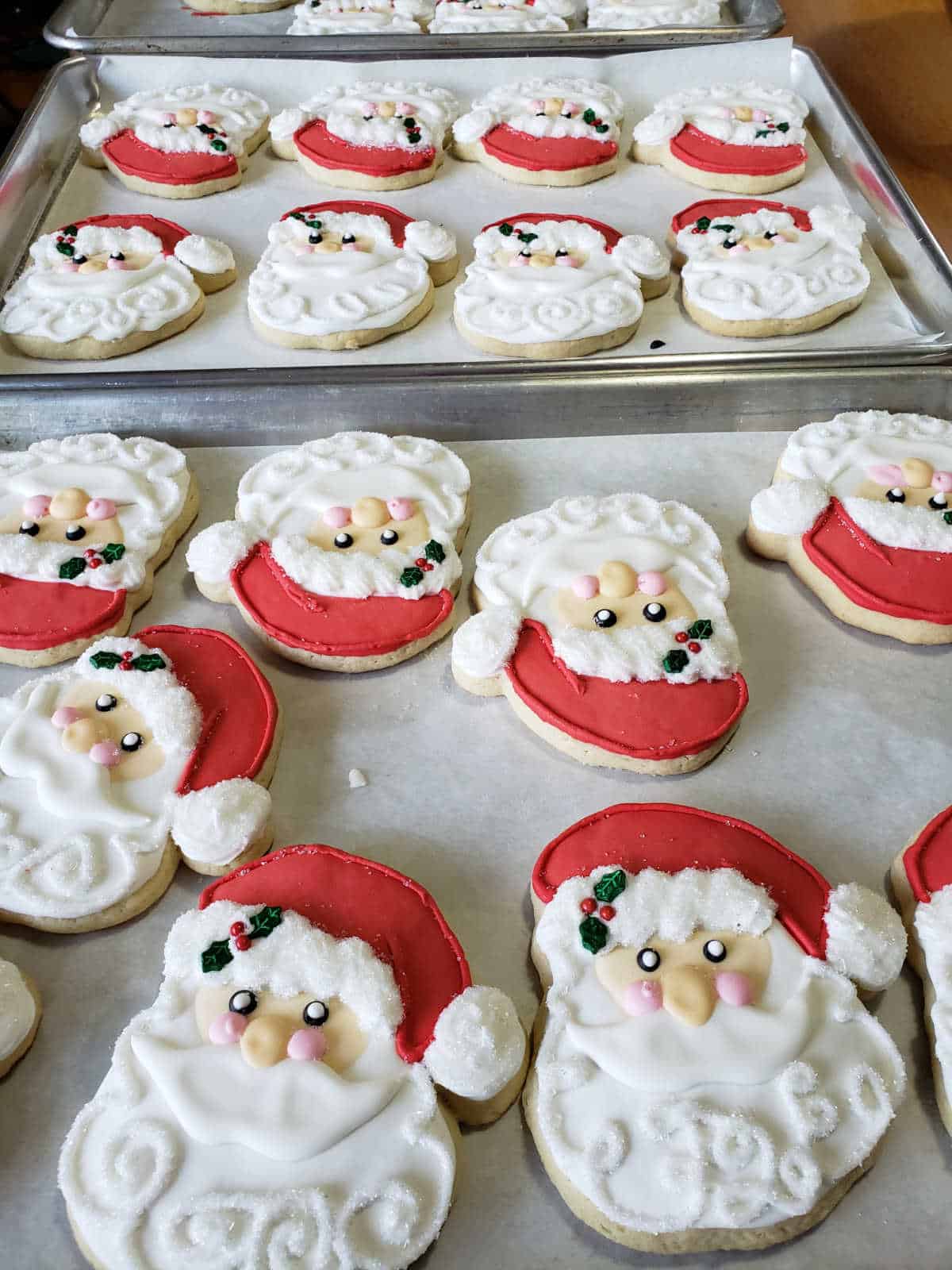 Santa faces sugar cookies decorated with royal icing drying on sheet pan.