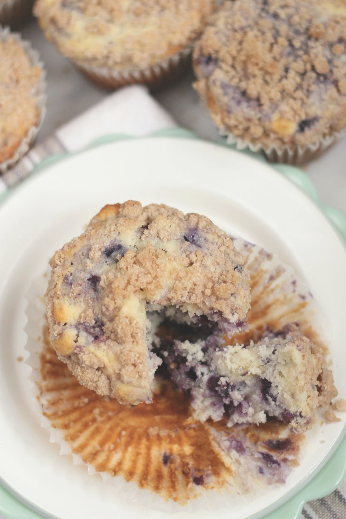 Close up of blueberry muffin with crumb topping, piece missing out of it.