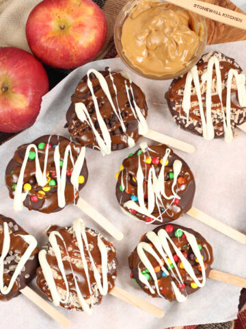 Caramel apple slices covered in chocolate and candies, toasted coconut on sheet pan.