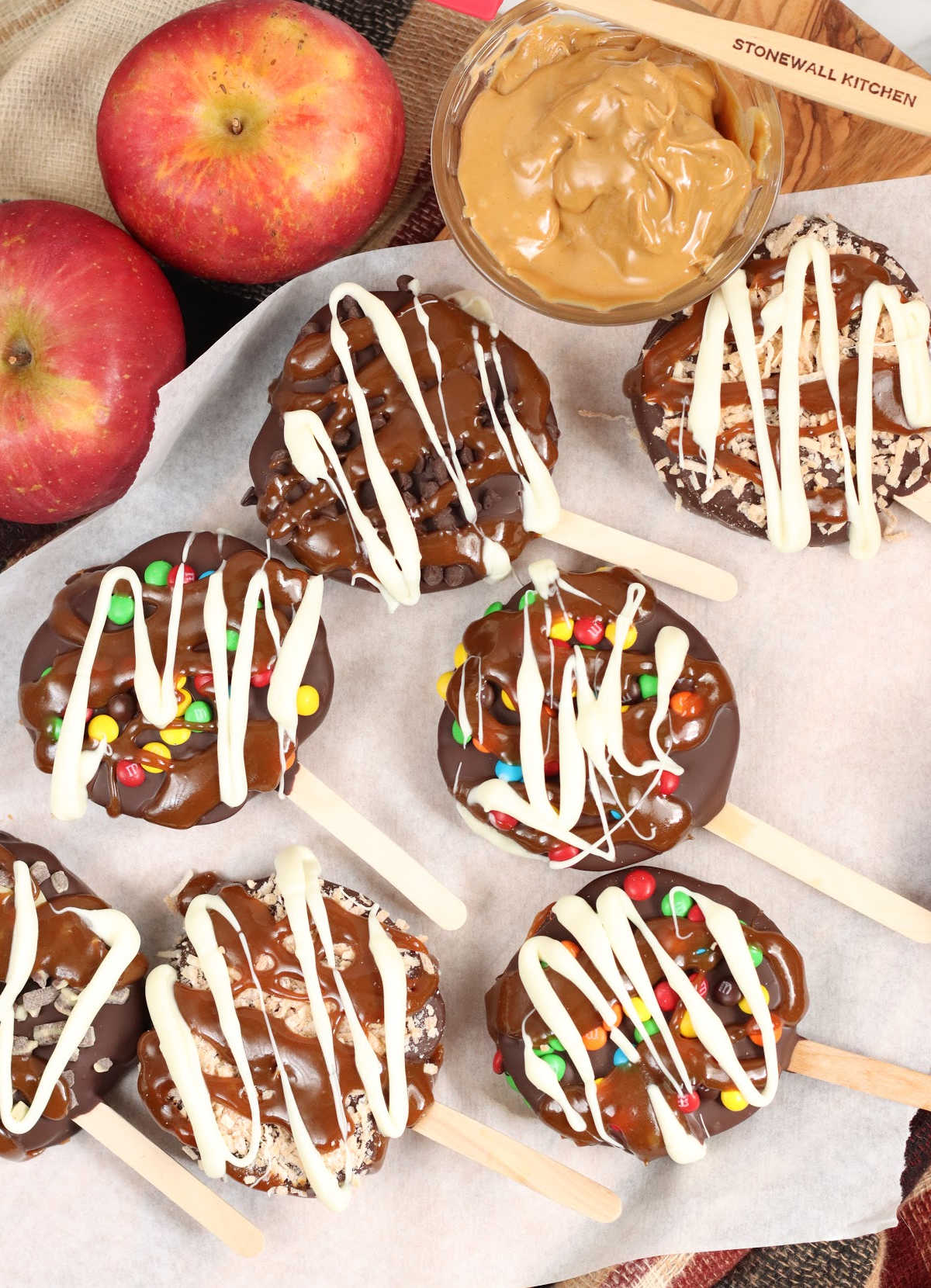 Caramel apple slices covered in chocolate and candies, toasted coconut on sheet pan.