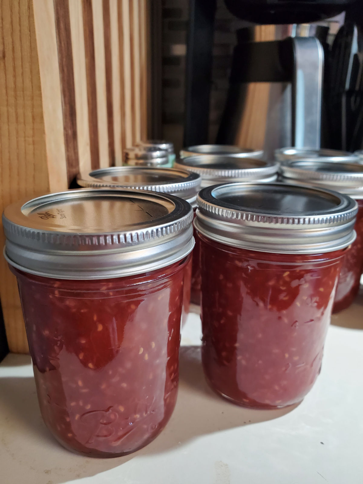 Pint Mason jars of homemade jam on kitchen counter next to stove.