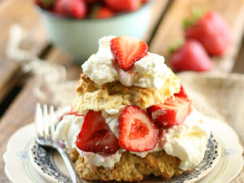 Strawberry shortcake, fresh strawberries, whipped cream on small white plate.