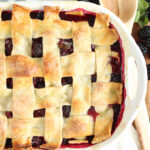 Cobbler with blackberries and lattice pie crust in white baking dish.