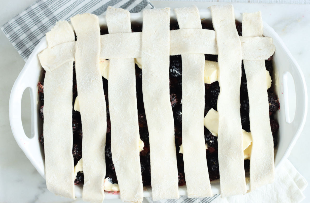 Cobbler with blackberries and weaving lattice pie crust.