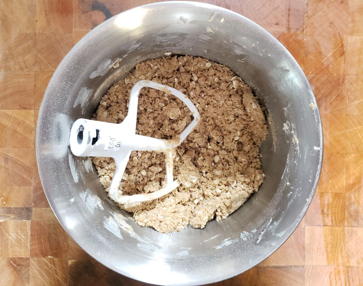 Apple crumble topping in stand mixer mixing bowl on butcher block.