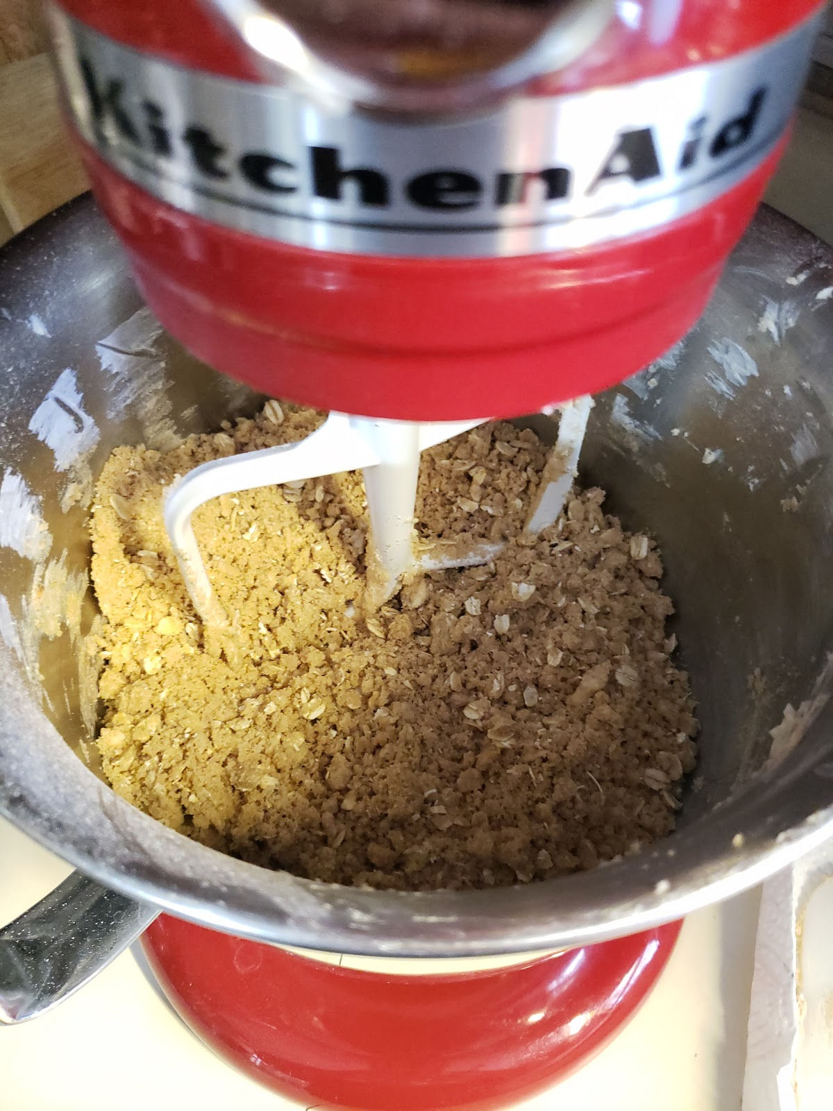 Red Kitchenaid mixer with apple crumble topping mixing.