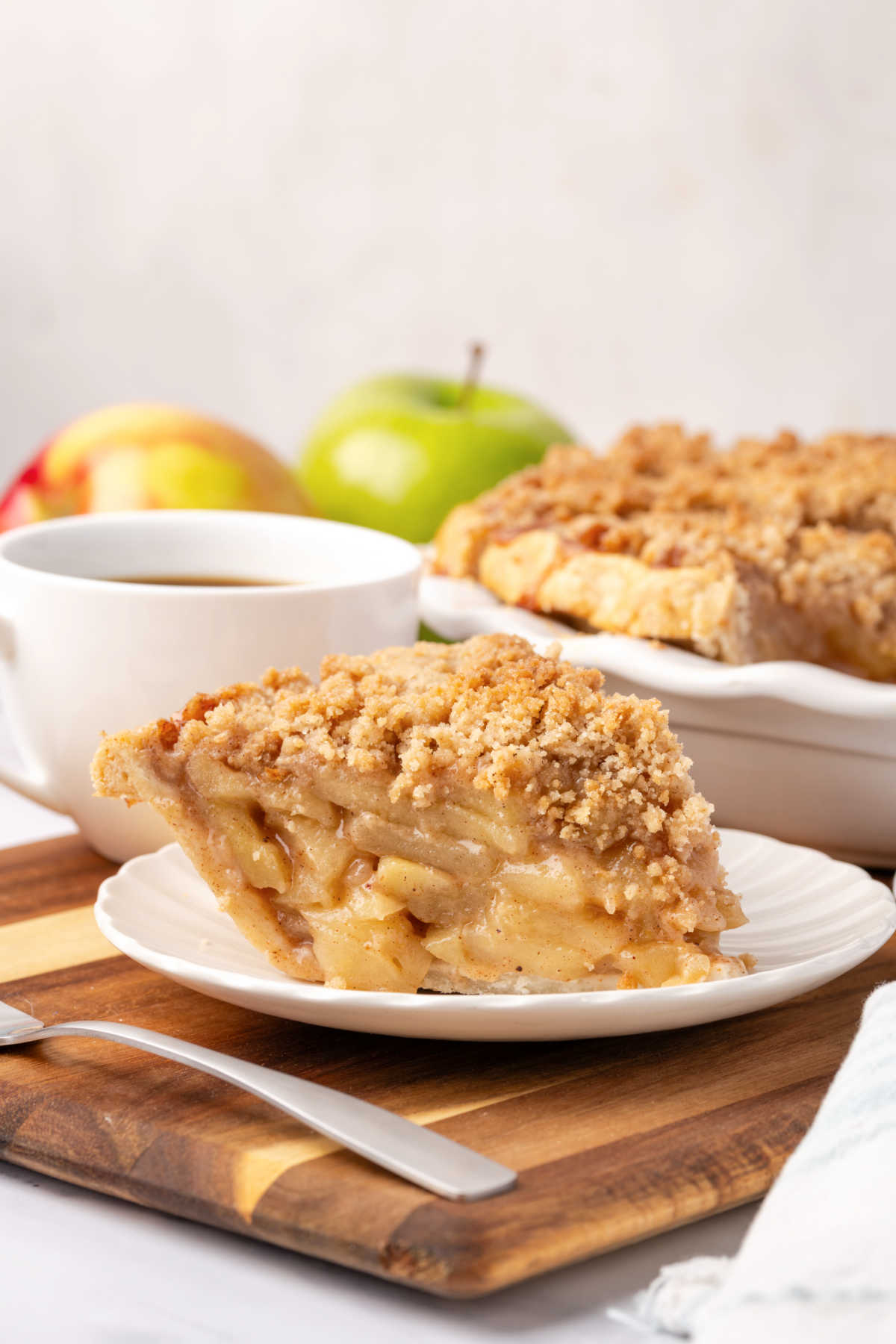 Slice of apple crumb pie on small white plate.