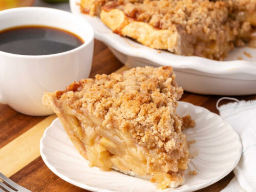 Slice of apple crumb pie on small white plate.