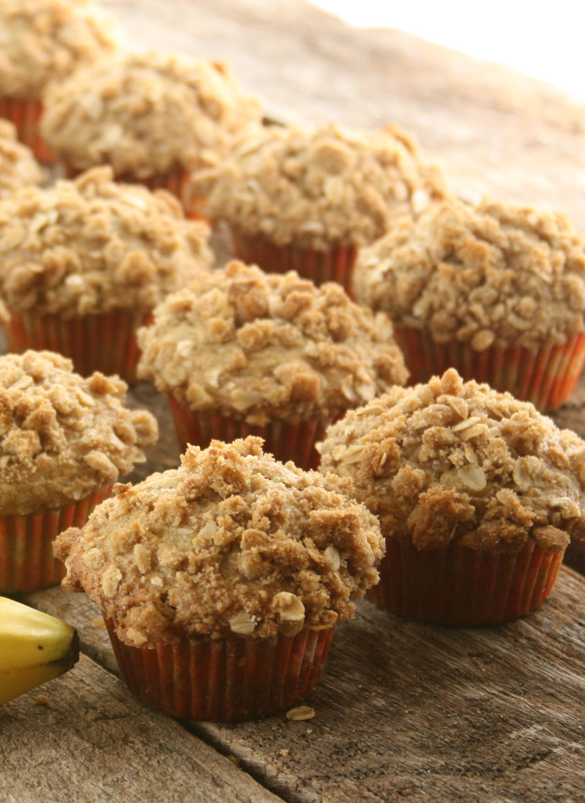 Banana muffins with oatmeal crumb topping on reclaimed wood boards.