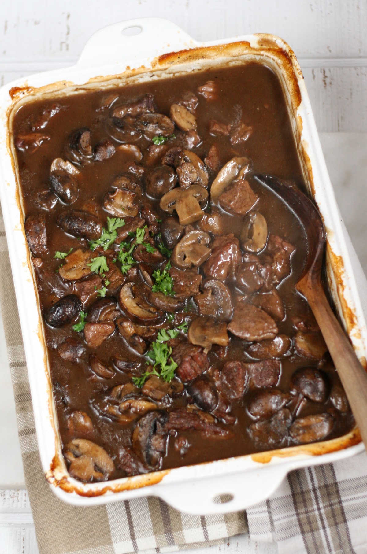 Beef tips gravy and mushrooms in white rectangle baking dish.