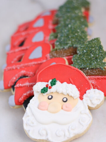 Santa face sugar cookies, red truck sugar cookies in background.