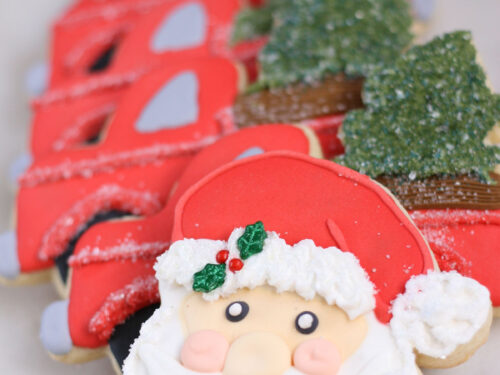 Santa face sugar cookies, red truck sugar cookies in background.