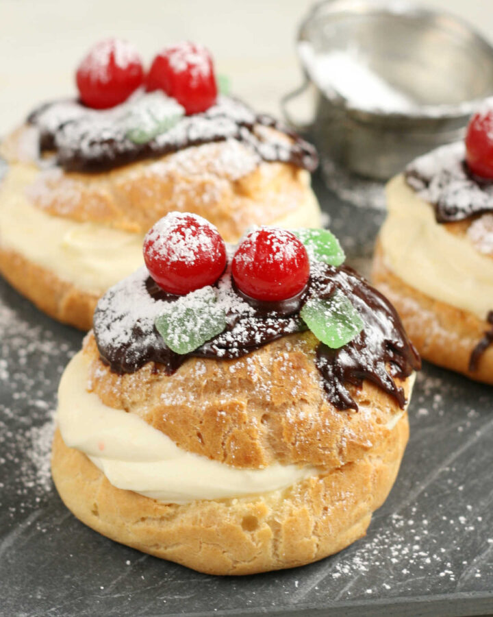 Cream puffs pastry cream and chocolate ganache, maraschino cherries and powdered sugar.