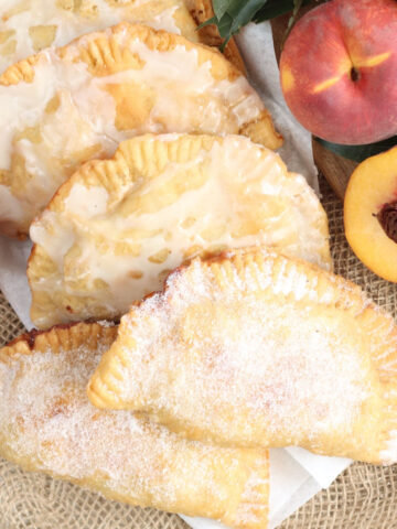 Hand pies on burlap, fresh peaches around.