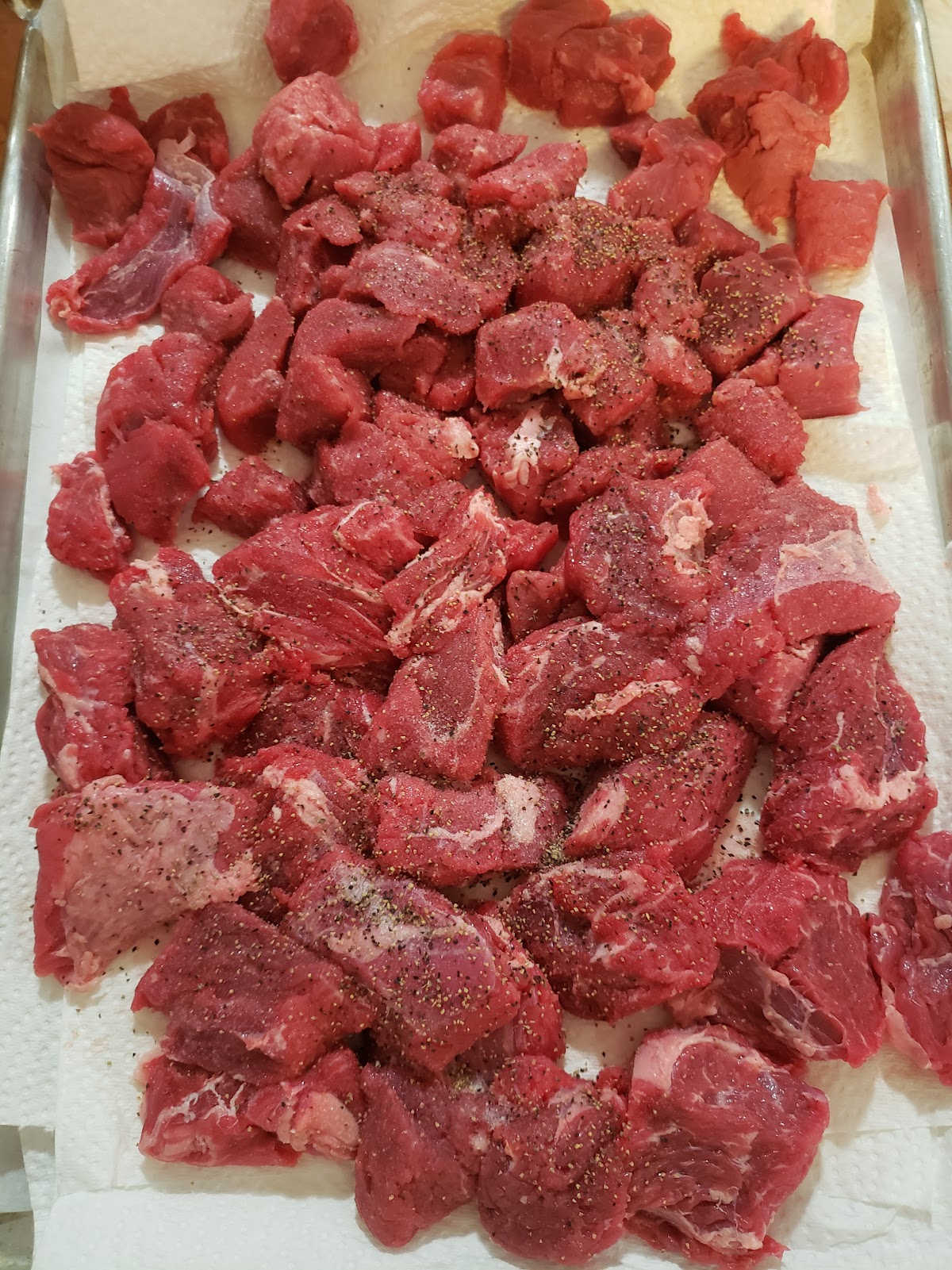Stew beef on sheet pan with paper towels, seasoned with salt and pepper.