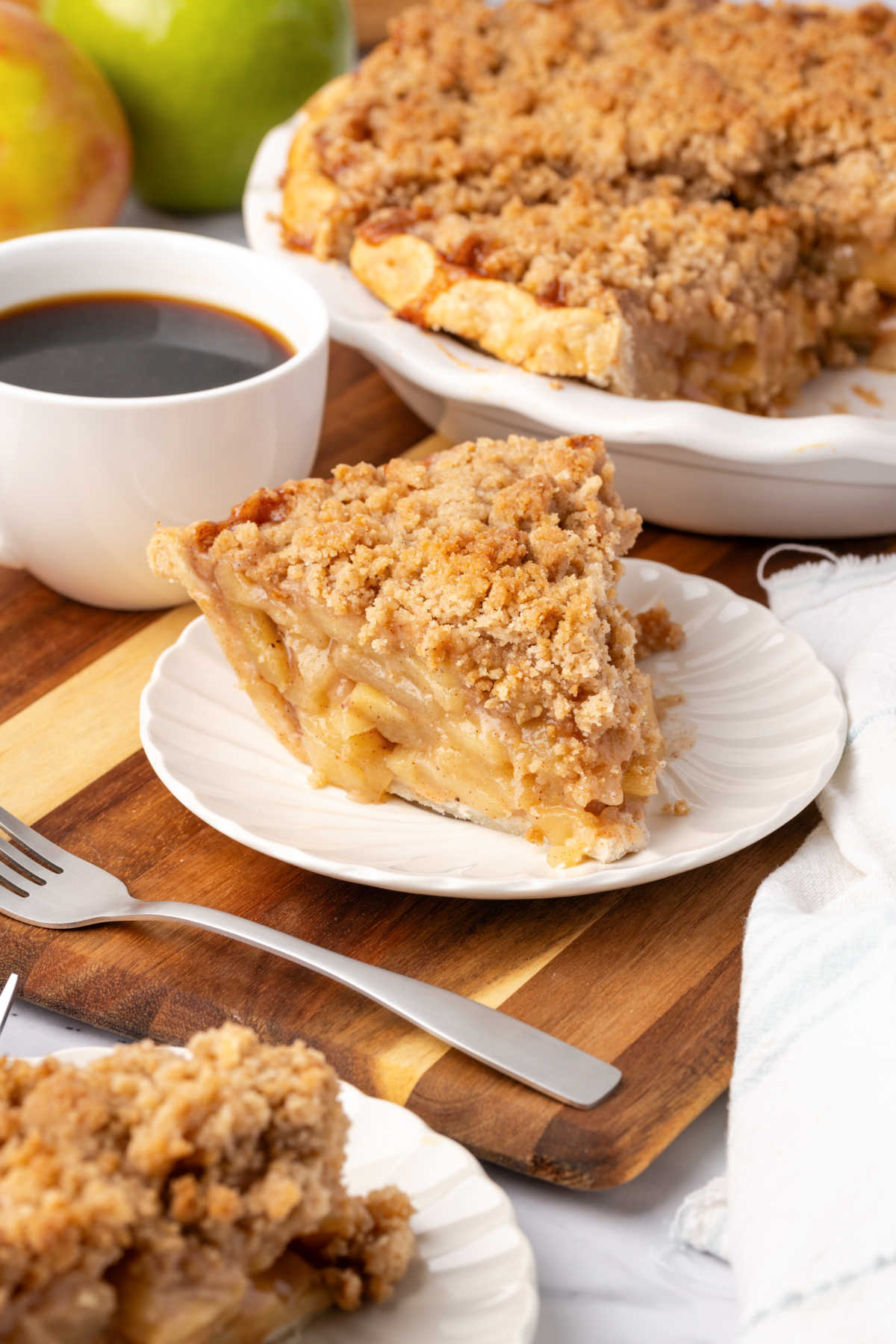 Slice of apple crumb pie on small white plate.