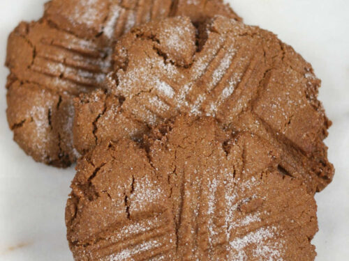 Molasses cookies lined up against each other on white marble.