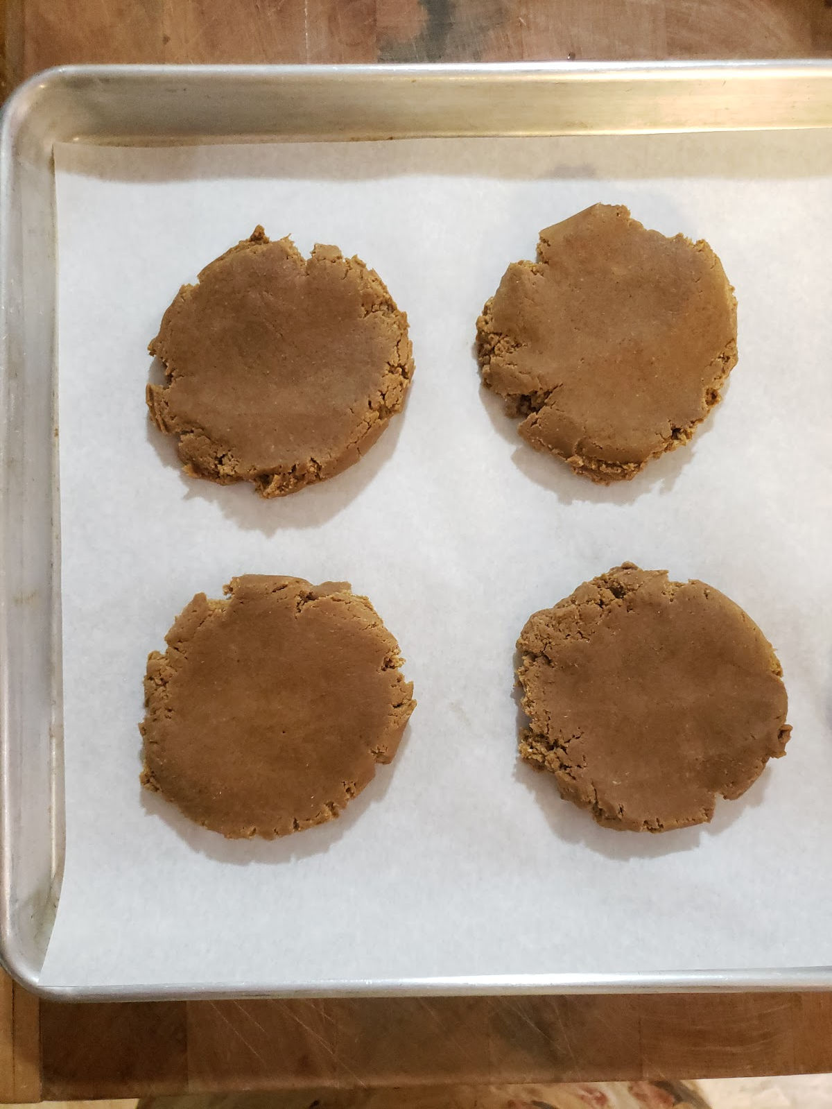 Pressed down molasses cookie dough on sheet pan with white parchment paper.