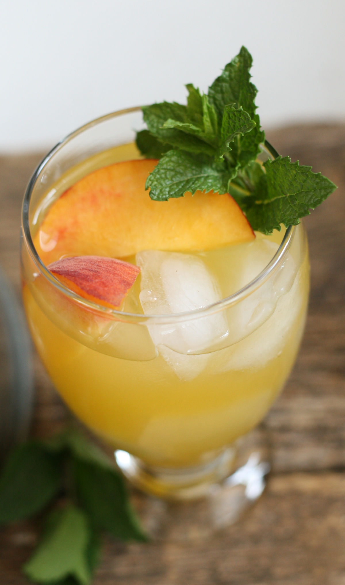 Close up of glass drink dispsenser filled with summer sangria, ice cubes, and peach slices.