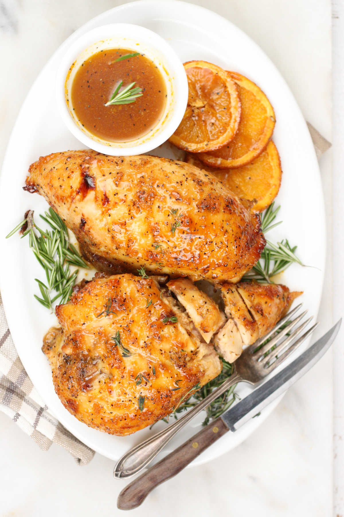 Glazed chicken breasts on oval white plate with dipping sauce.