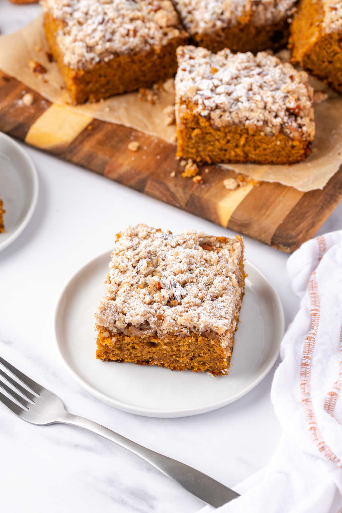 Pumpkin cake square on small white plate with fork.