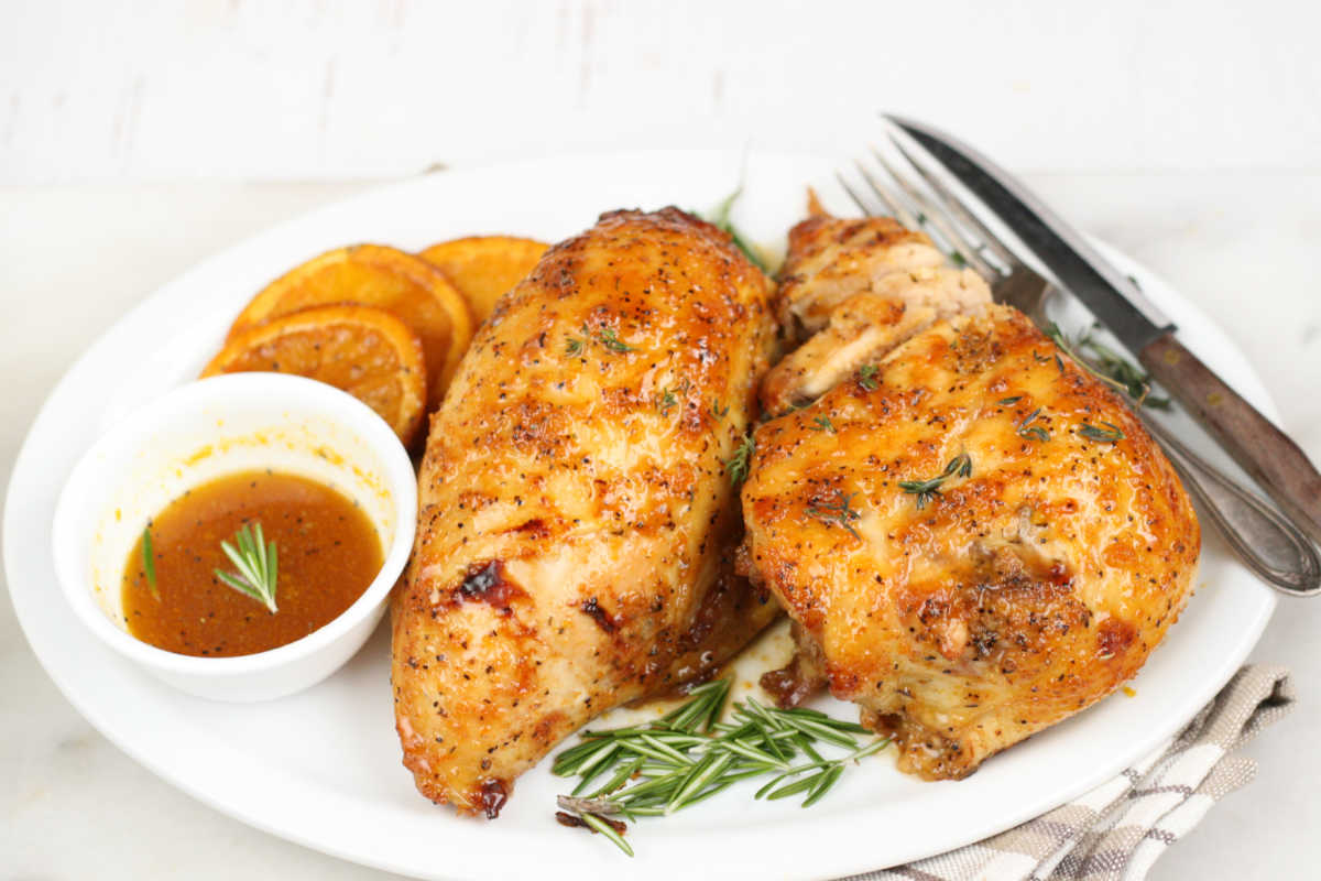 Two chicken breasts on an oval plate with honey orange glaze.