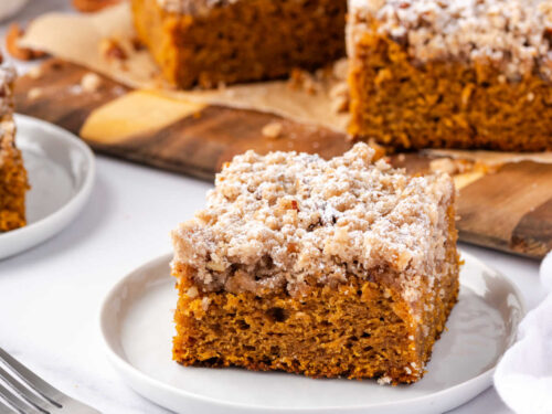 Square of pumpkin crumb cake on small white plate with fork.