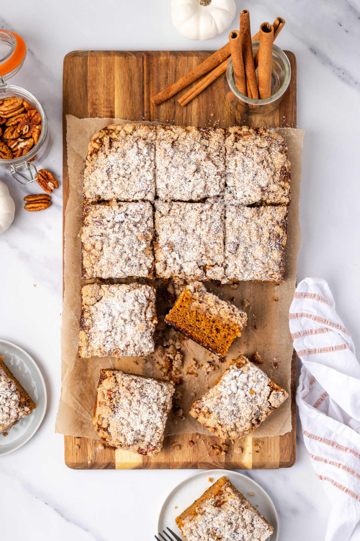 Overhead shot of pumpkin crumb cake squares on wood cutting board.