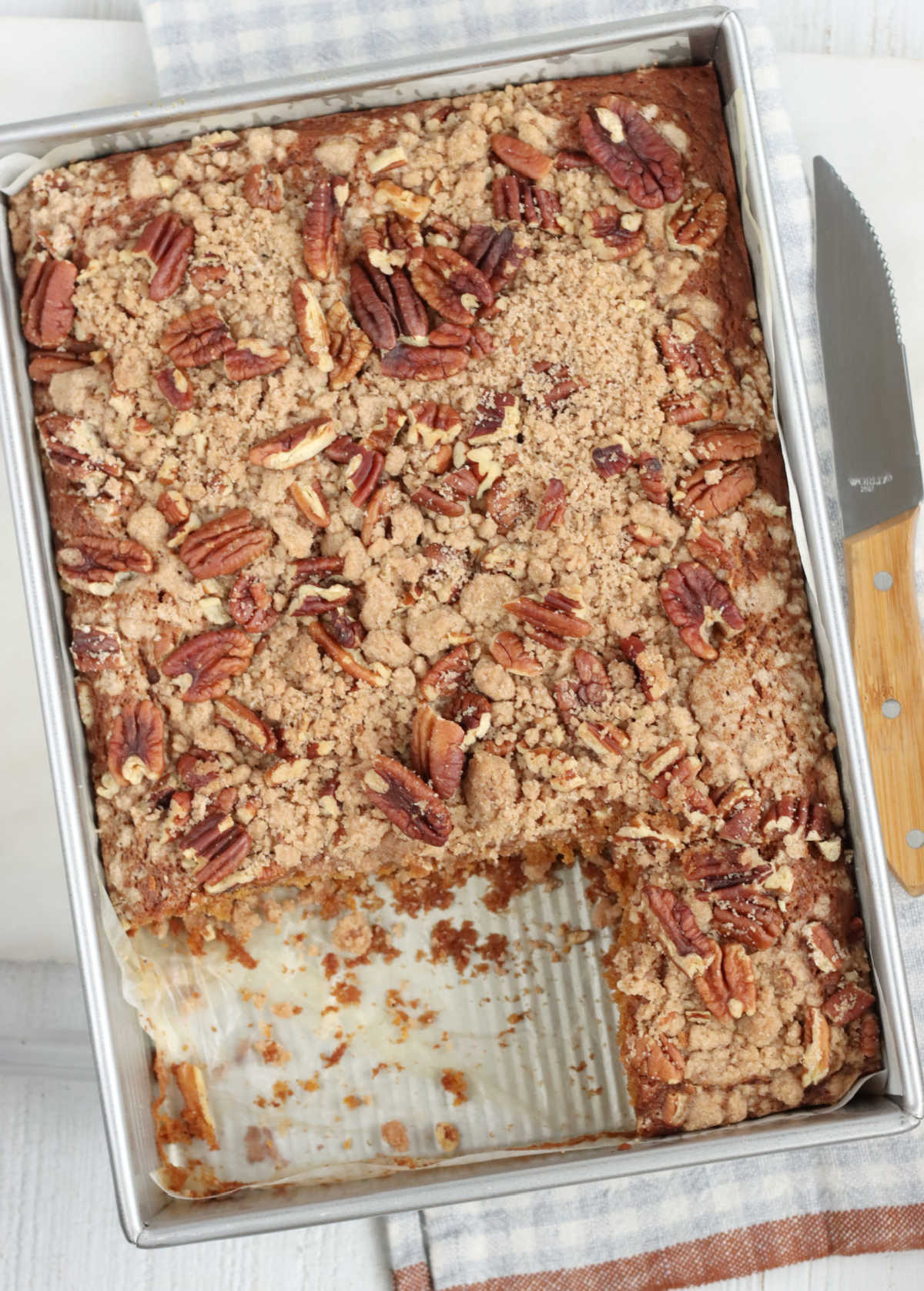 Rectangle baking pan with cake with crumb and pecan topping.