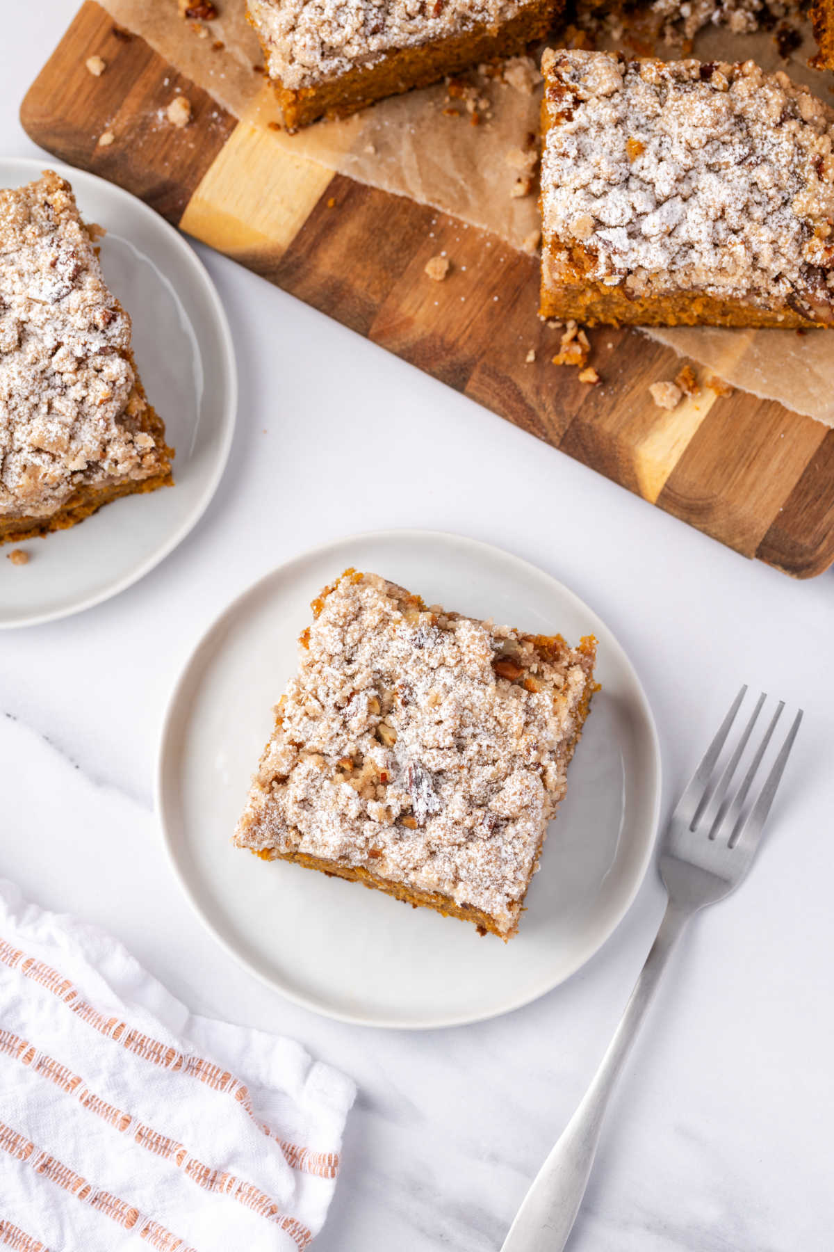 Pumpkin cake cut into squares, one on small white plate with fork.