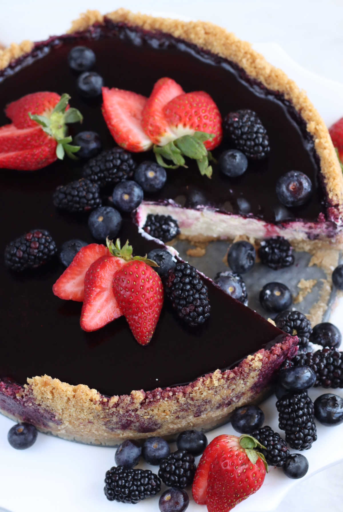 Cheesecake with berry topping, graham cracker crust, fresh berries with slice cut out.