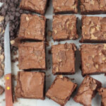 Squares of brownies with Heath bar pieces on white marble.