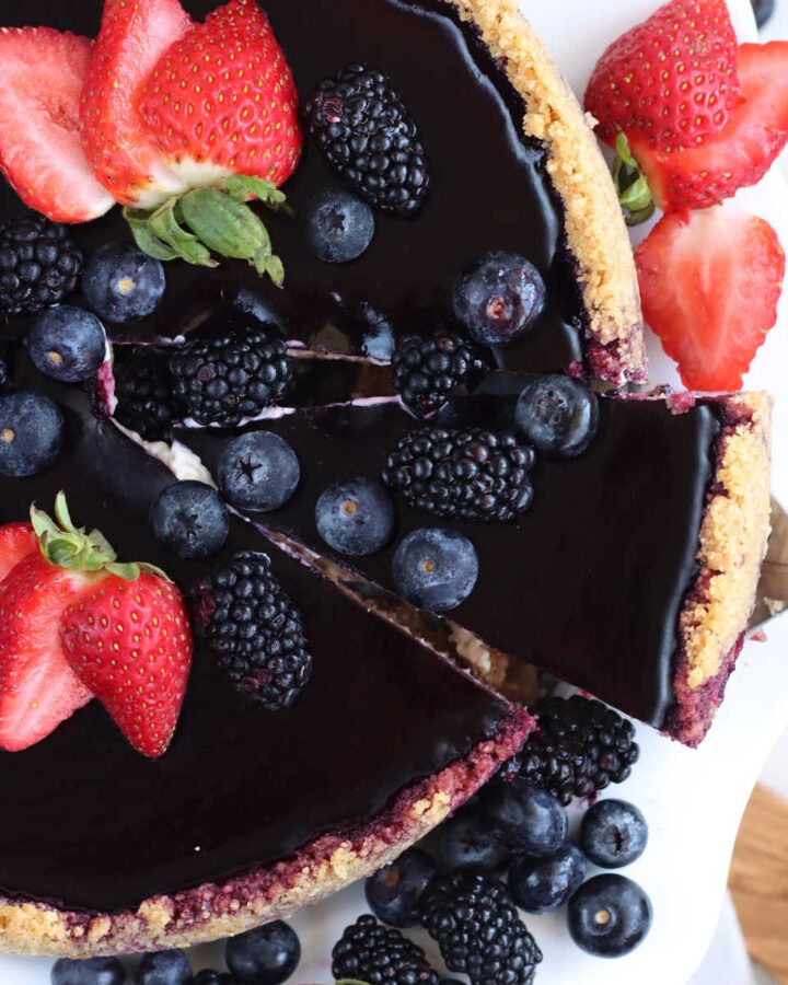 Slice with berries out of whole cheesecake.