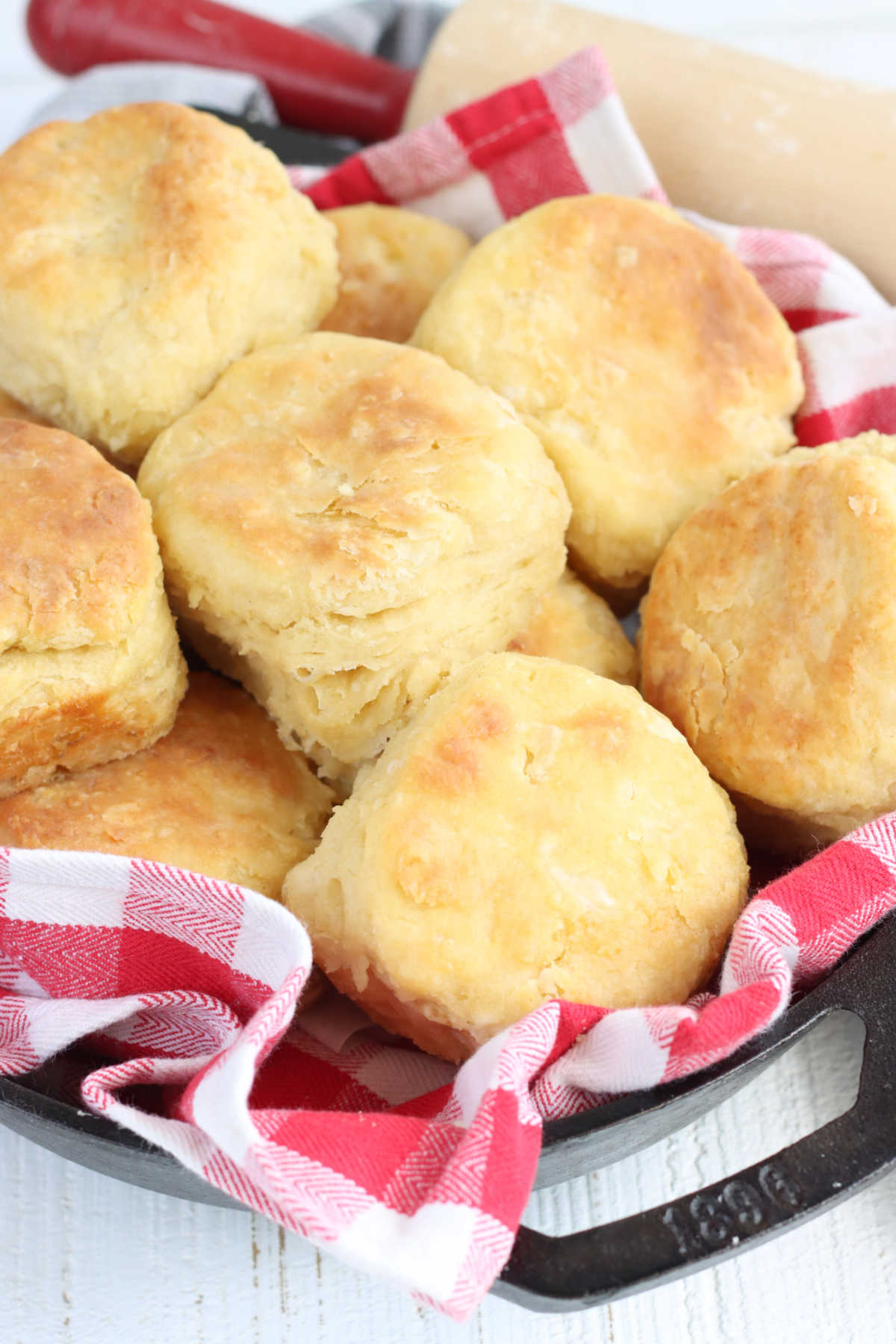 Biscuits in cast iron skillet with red and white checkered kitchen towel.