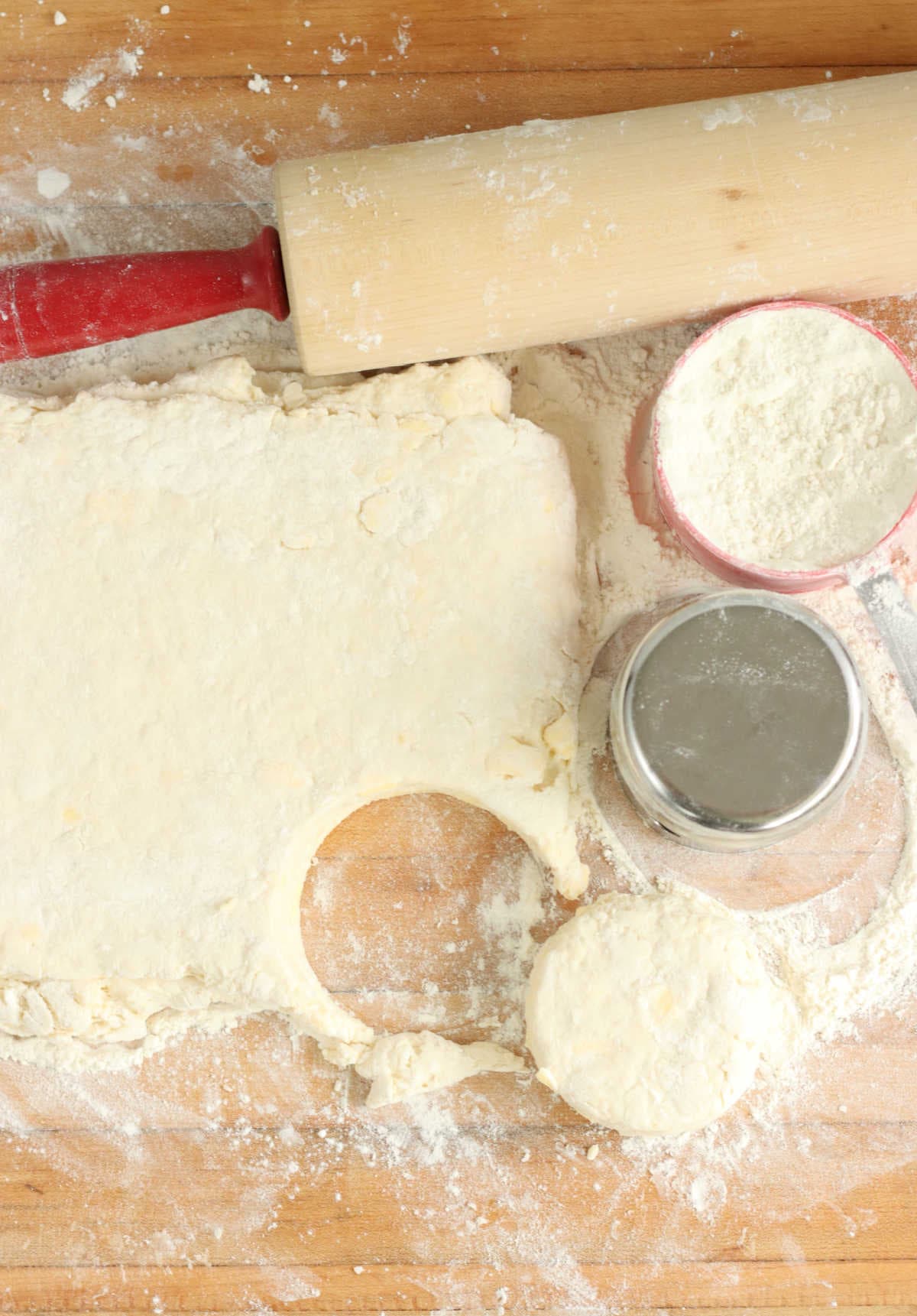 Cutting biscuits on butcher block with metal biscuit cutter.