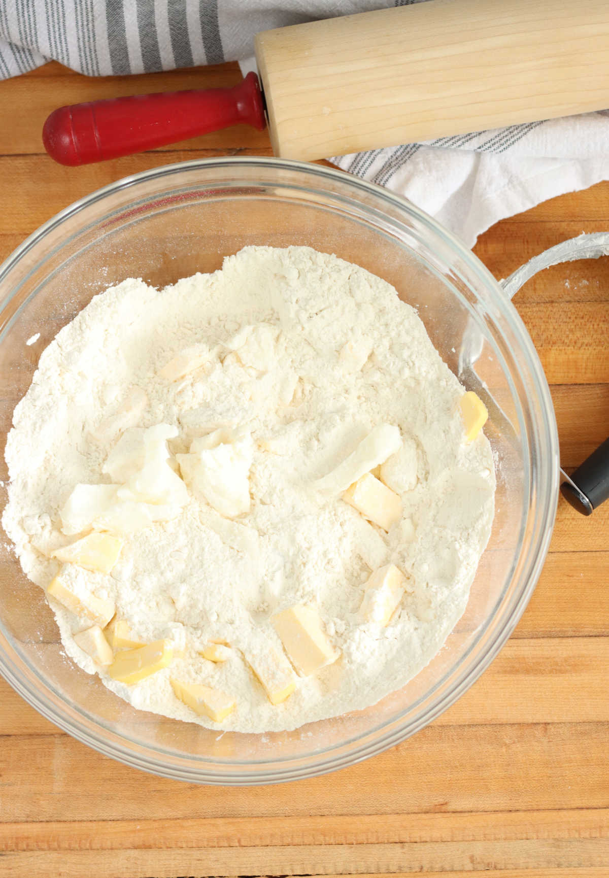 Flour, butter and lard in clear glass bowl on butcher block.