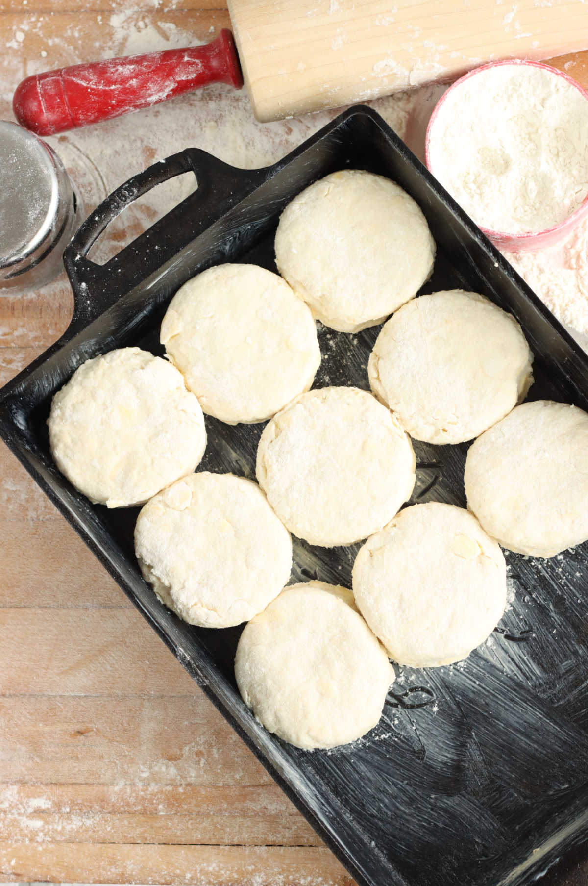 Unbaked biscuits in rectangle cast iron baking pan on butcher block.