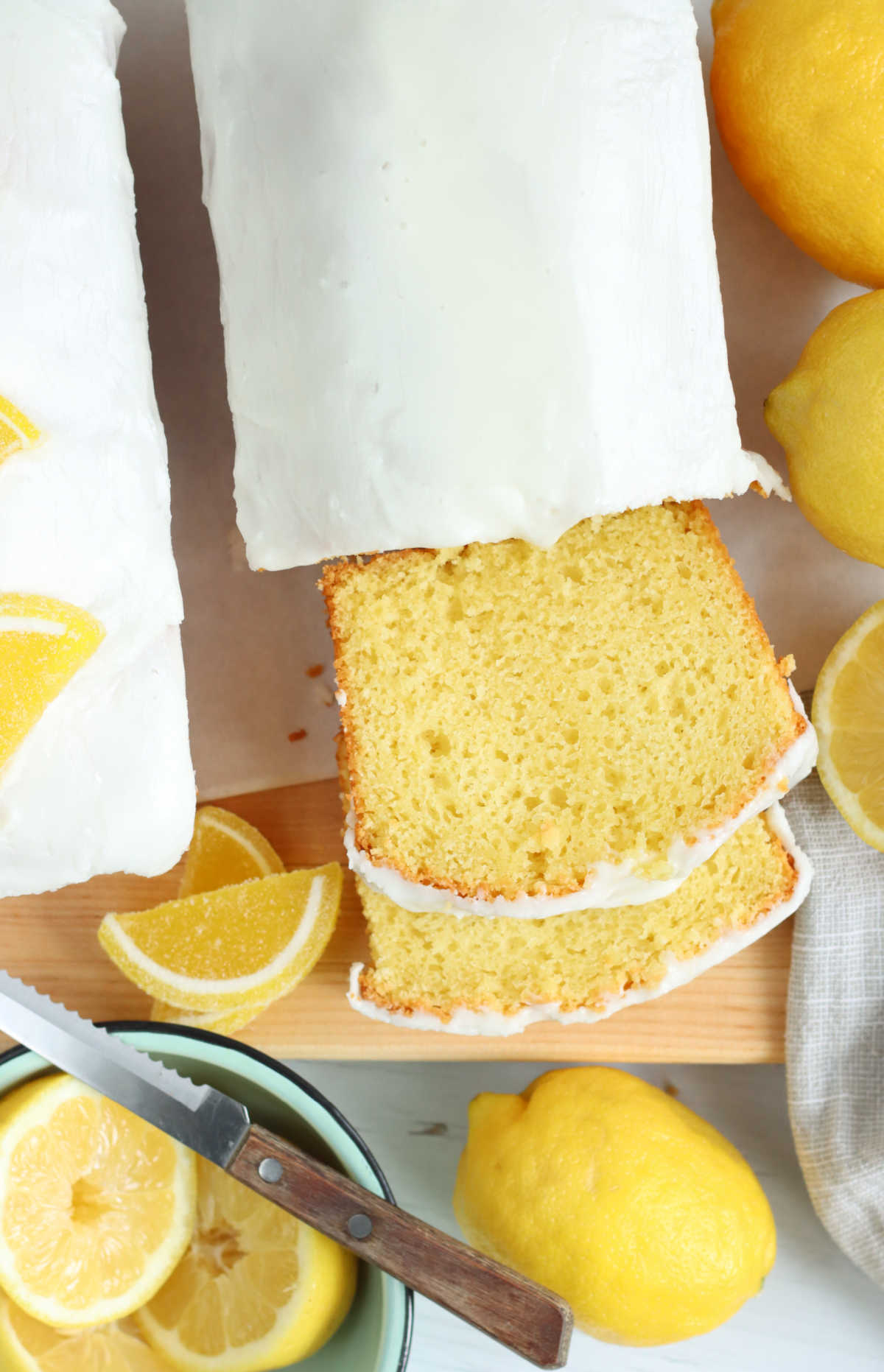 Two yellow loaf cakes, one partially sliced, lemons to side.