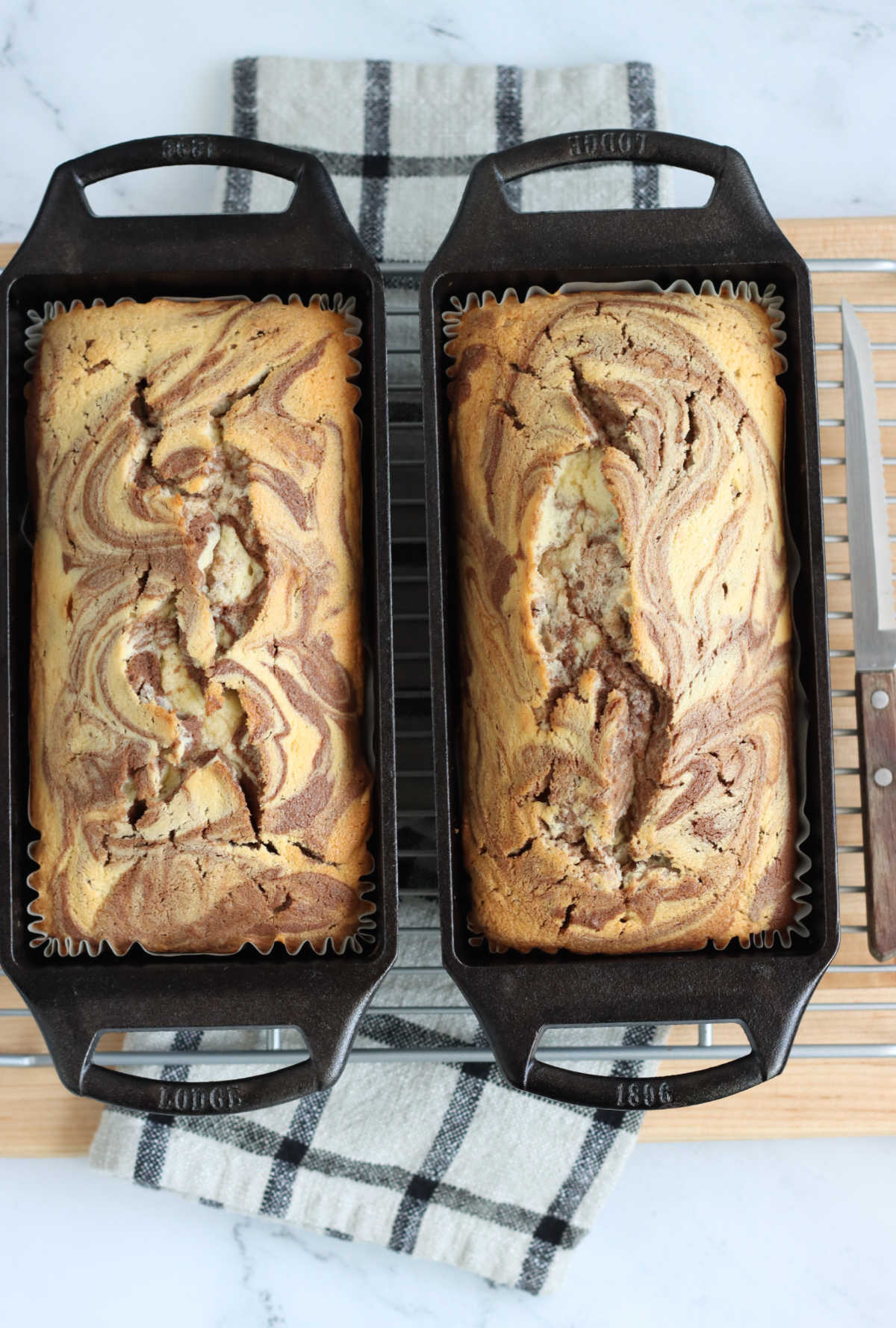Marble cake in two cast iron loaf pans on wooden cutting board.