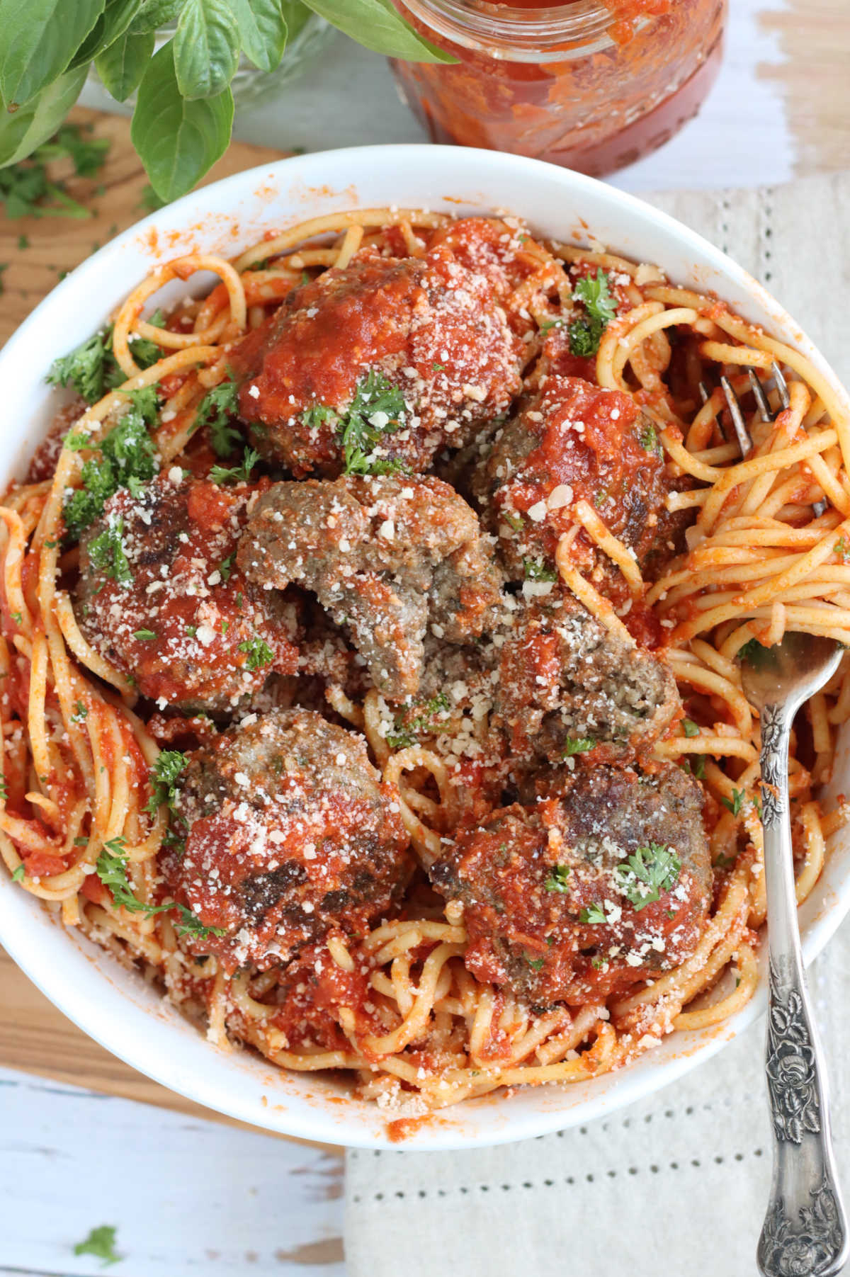 Spaghetti and meatballs in white bowl with fork on right.