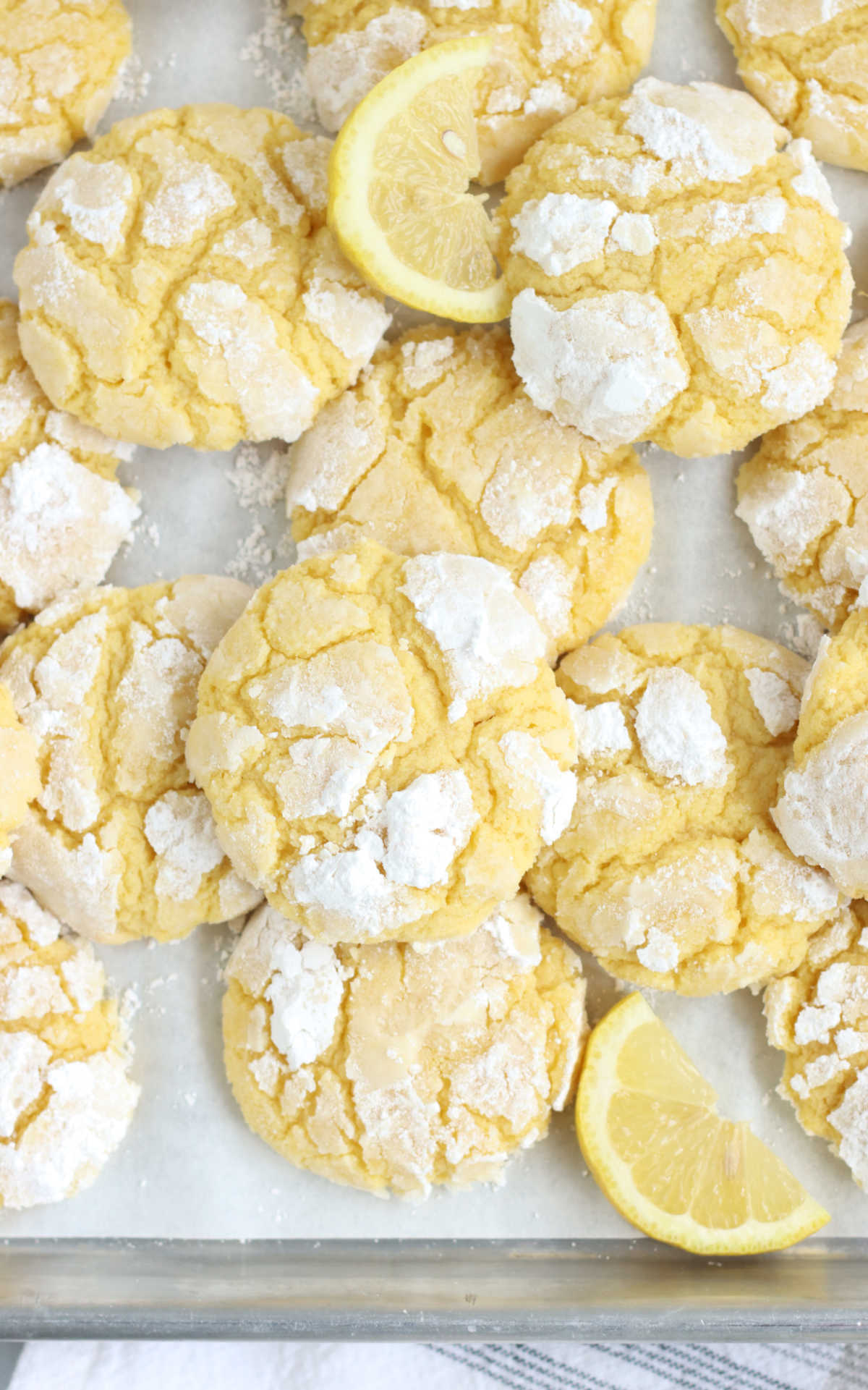 Lemon cookies on half sheet pan with lemon wedges.