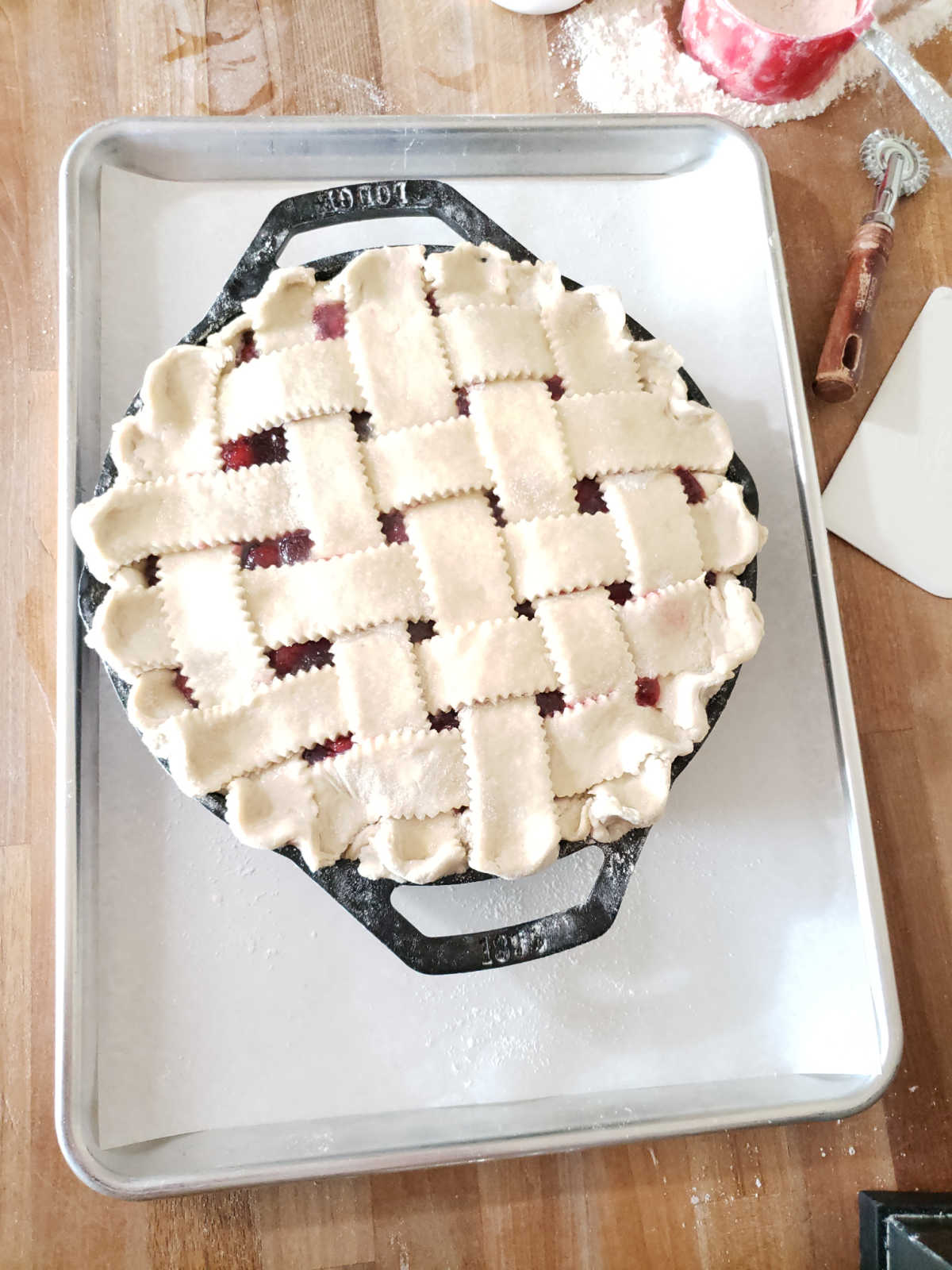 Unbaked cherry pie with lattice crust in dual handle cast iron pan.